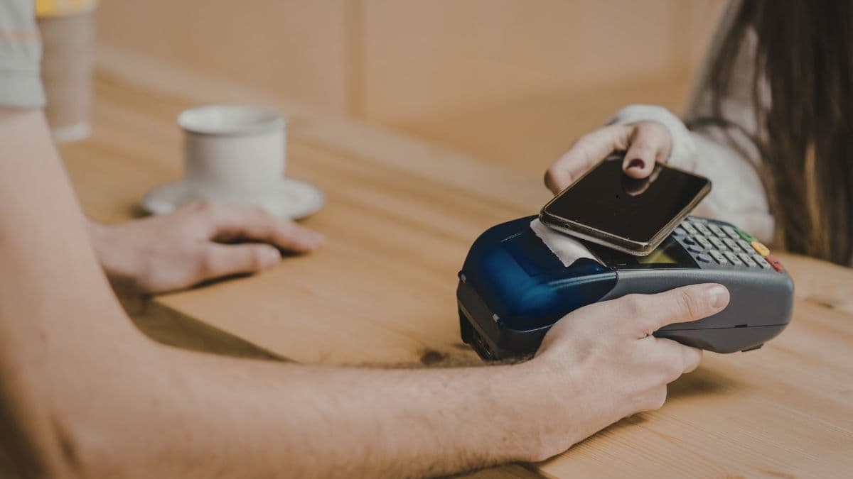 Australian merchant at point of sale comparing QR code payment with card terminal on a countertop